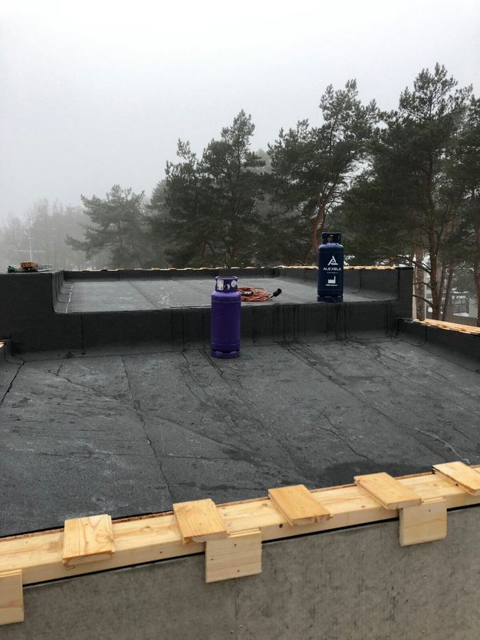 Lamekatuse bituumenkate ja puidust parapetitoestus, gaasiballoonid kõrval